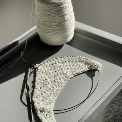 A detailed view of crochet work in progress using white yarn and a crochet hook.