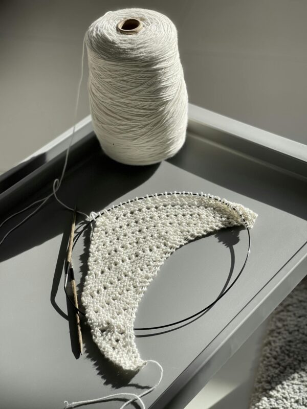 A detailed view of crochet work in progress using white yarn and a crochet hook.