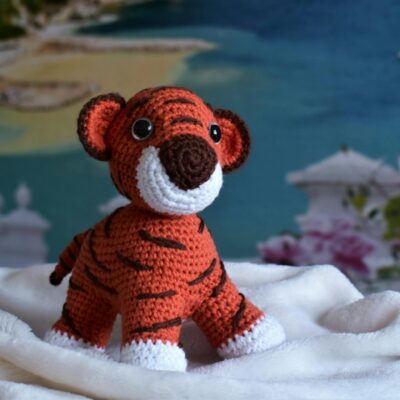 Close-up of a handmade crochet tiger amigurumi toy on a cozy white blanket.