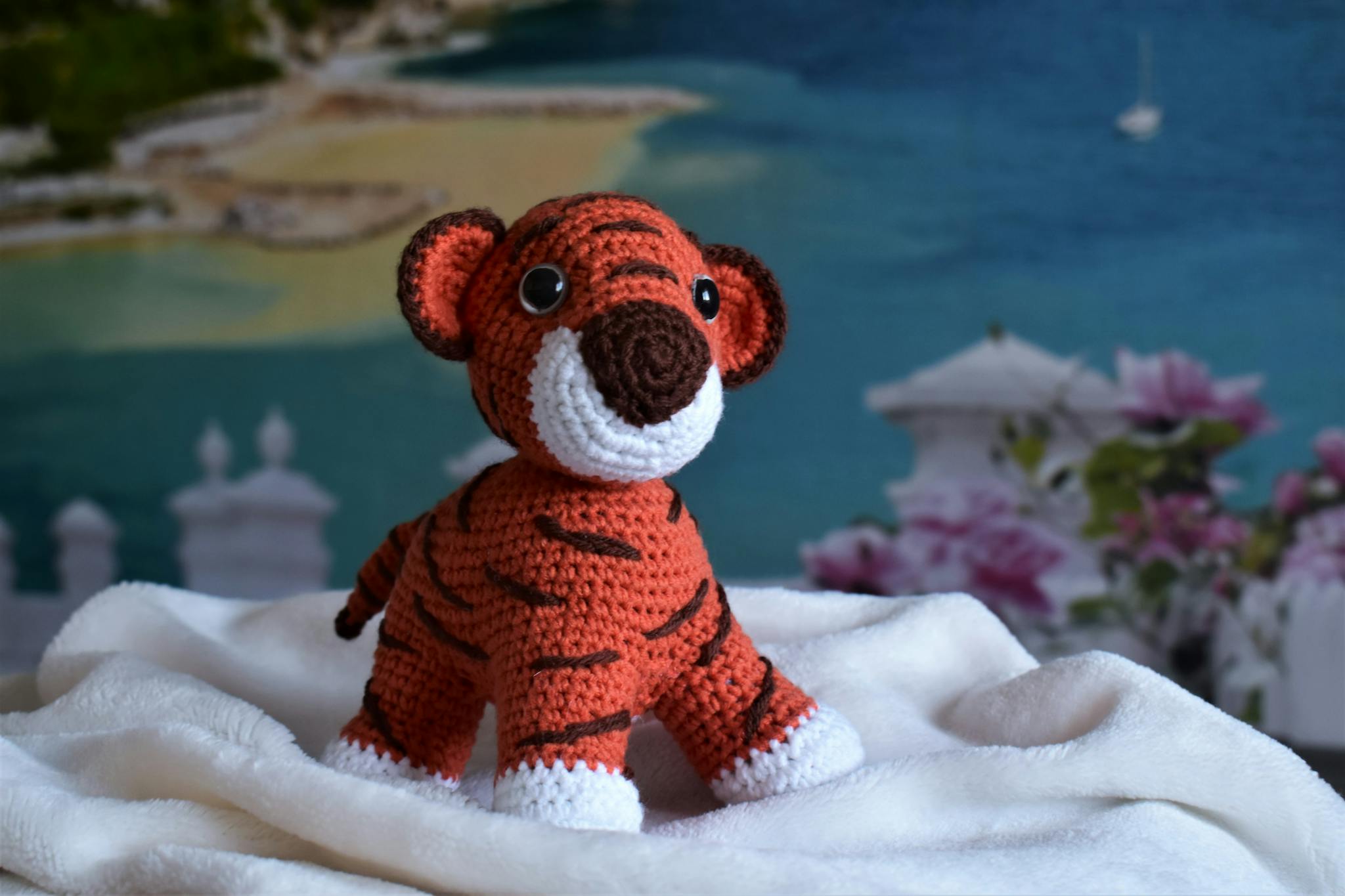 Close-up of a handmade crochet tiger amigurumi toy on a cozy white blanket.