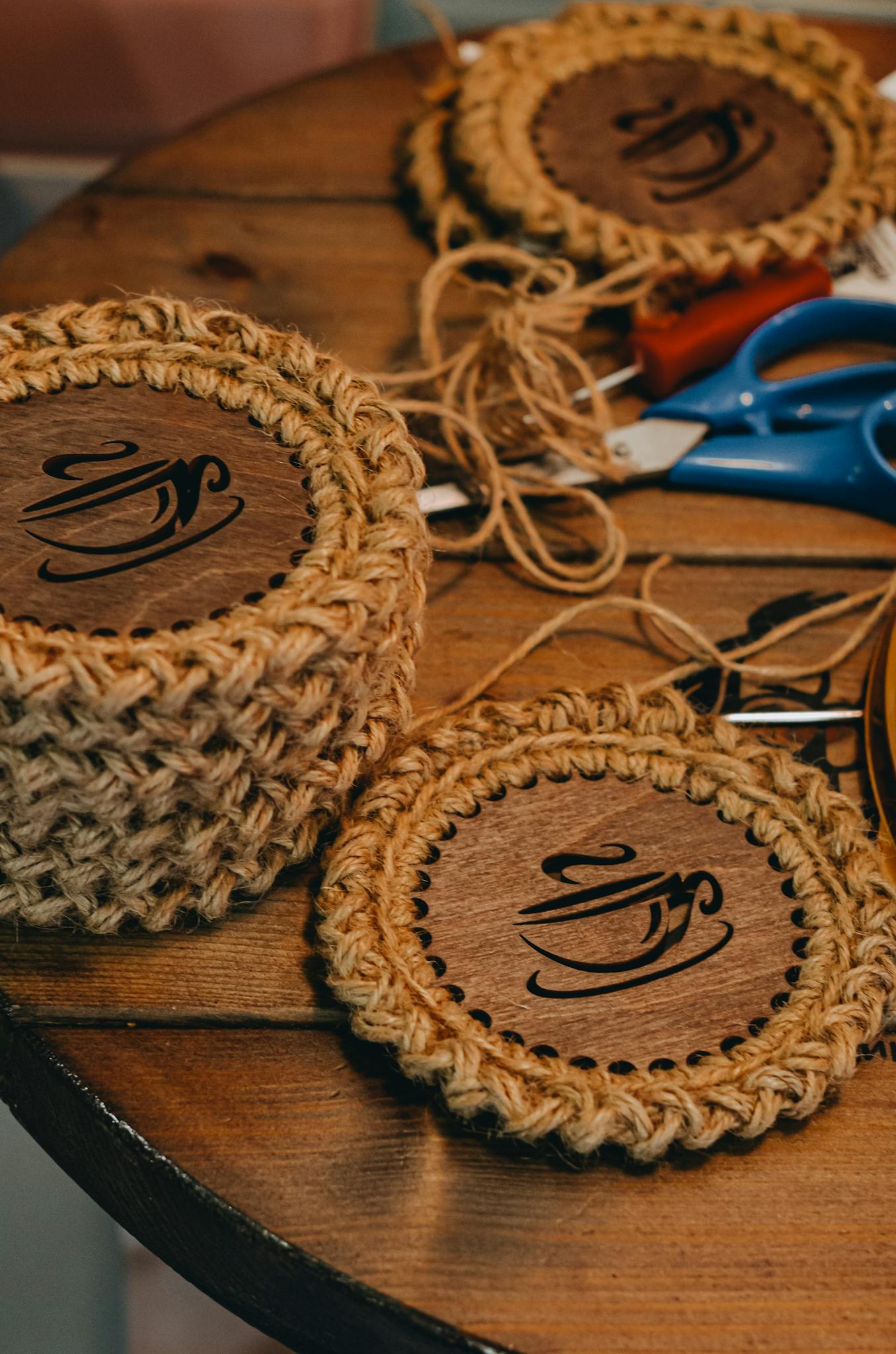 Close-up of handmade crochet wood coasters on a wooden table, showcasing arts and crafts.