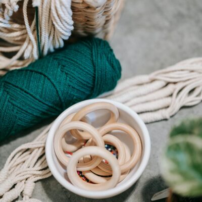 Crafting supplies arrangement featuring wooden rings, colorful threads, and a woven basket.