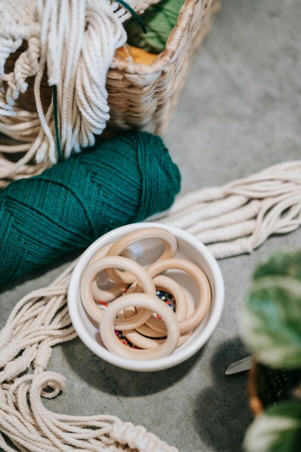 Crafting supplies arrangement featuring wooden rings, colorful threads, and a woven basket.