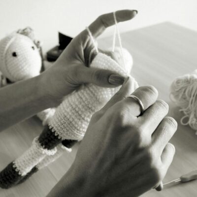 Hand crafting a crochet toy in a black and white setting, showcasing detailed needlework.