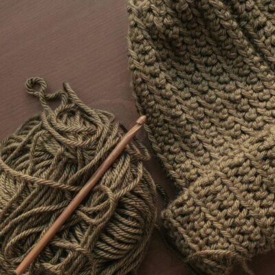 Handcrafted knit hat with yarn and crochet hook on a wooden table.